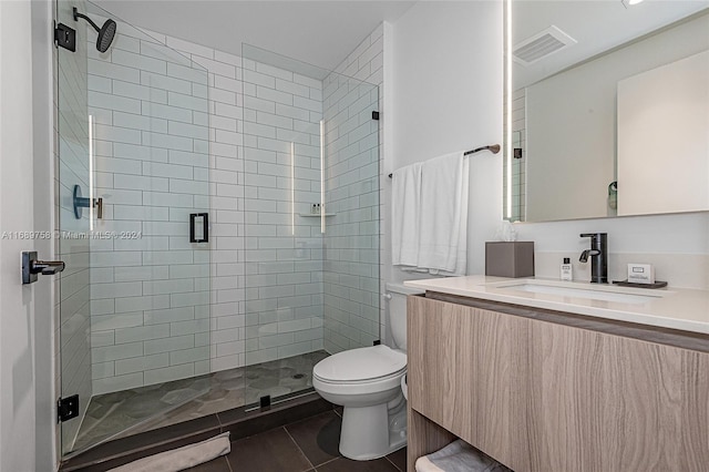 bathroom with toilet, vanity, tile patterned floors, and a shower with door