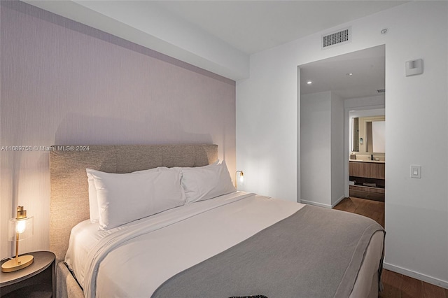 bedroom featuring hardwood / wood-style flooring and connected bathroom