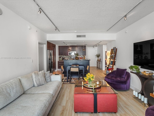 living room with a textured ceiling, track lighting, and light hardwood / wood-style flooring