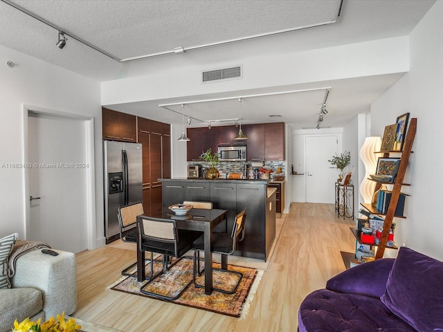 dining space with light wood-type flooring, a textured ceiling, and rail lighting