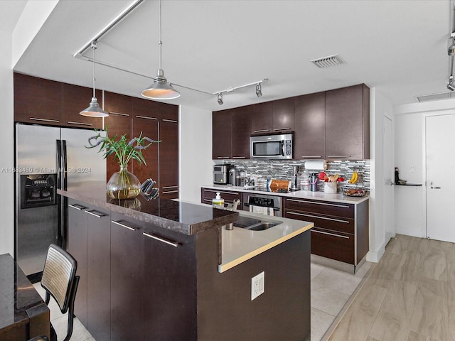 kitchen featuring backsplash, appliances with stainless steel finishes, decorative light fixtures, dark brown cabinets, and sink