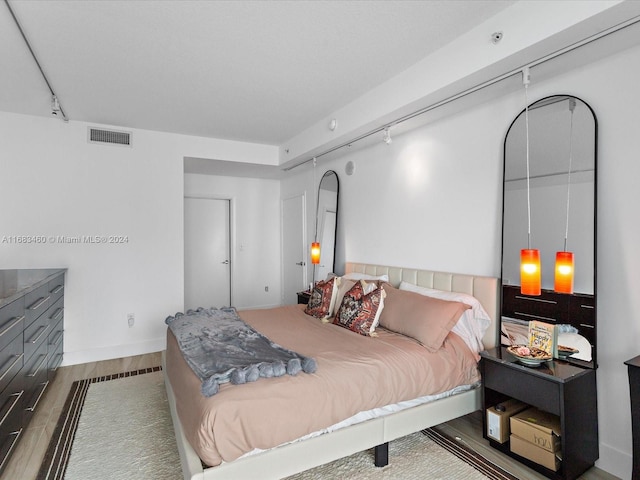 bedroom featuring wood-type flooring and track lighting