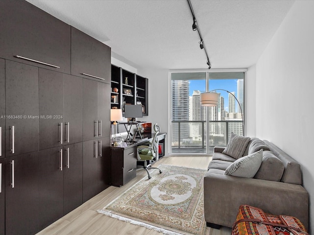 home office featuring light hardwood / wood-style floors, a wall of windows, rail lighting, and a textured ceiling