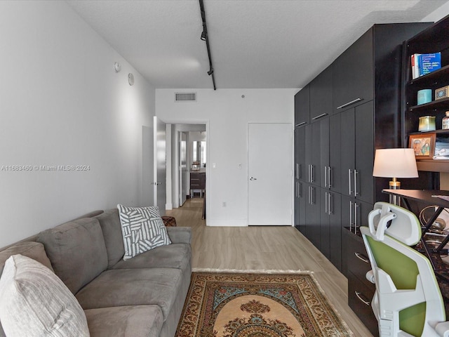 living room featuring light hardwood / wood-style flooring, a textured ceiling, and rail lighting