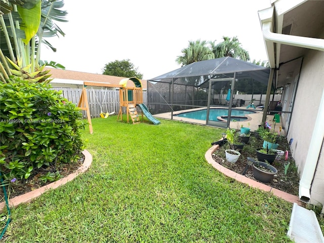 view of yard featuring a fenced in pool, glass enclosure, and a playground