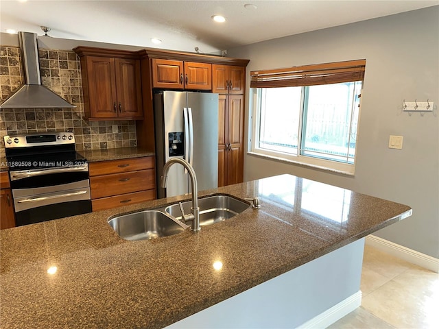 kitchen featuring wall chimney exhaust hood, sink, appliances with stainless steel finishes, dark stone counters, and backsplash