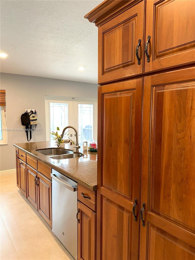 kitchen with sink, stainless steel dishwasher, a textured ceiling, and light stone counters