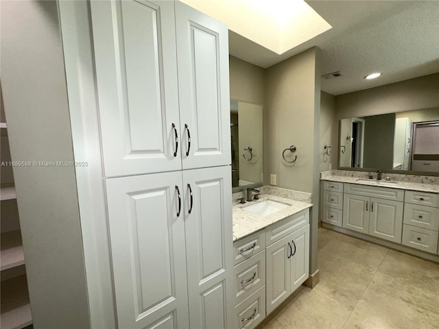 bathroom featuring tile patterned flooring, vanity, and a skylight