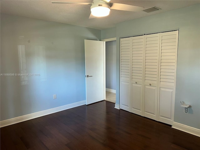 unfurnished bedroom featuring dark wood-type flooring, ceiling fan, a closet, and a textured ceiling