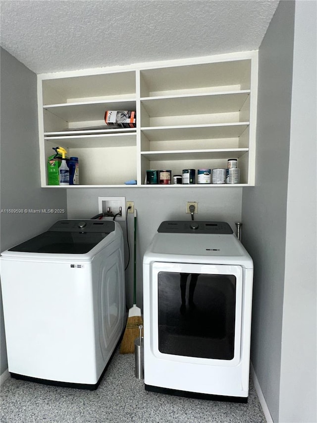 washroom with washing machine and clothes dryer and a textured ceiling