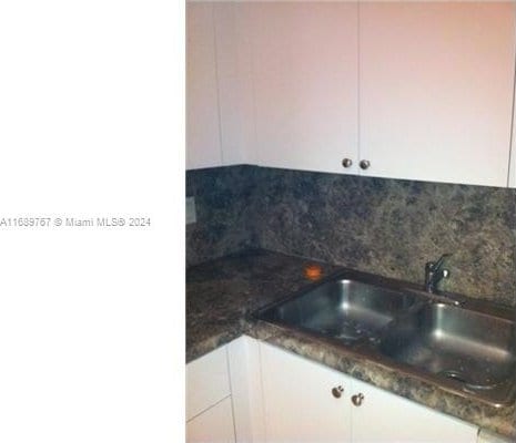 interior space with white cabinets, dark stone counters, tasteful backsplash, and sink