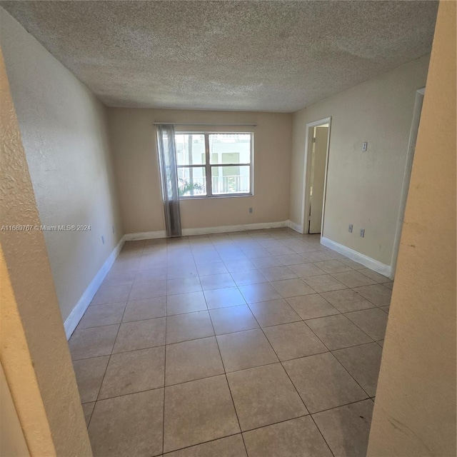 tiled empty room with a textured ceiling