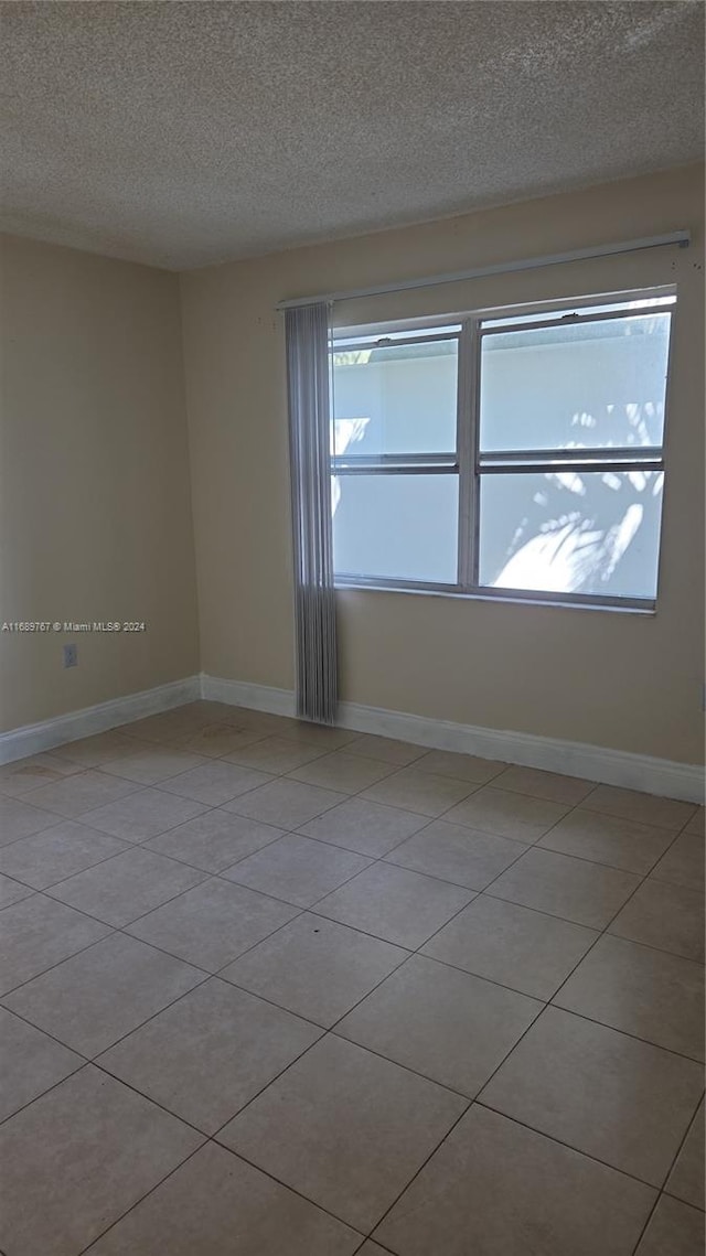 empty room with a textured ceiling and light tile patterned flooring