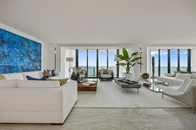 living room with plenty of natural light, a water view, and a wall of windows