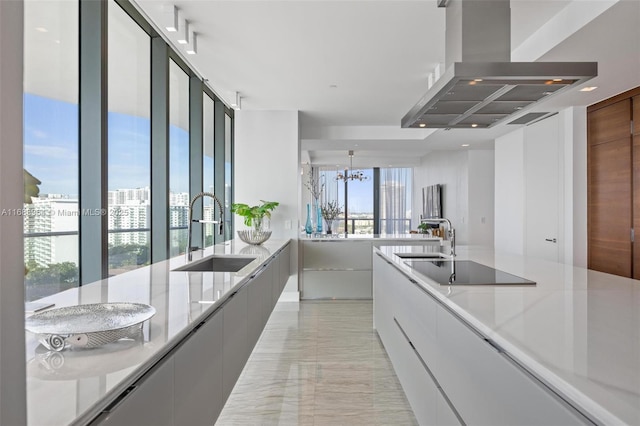 kitchen featuring light stone counters, black electric cooktop, sink, and range hood