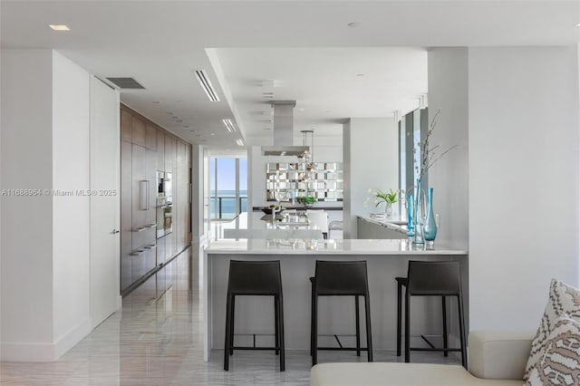 kitchen with a kitchen breakfast bar, stainless steel oven, kitchen peninsula, and island exhaust hood