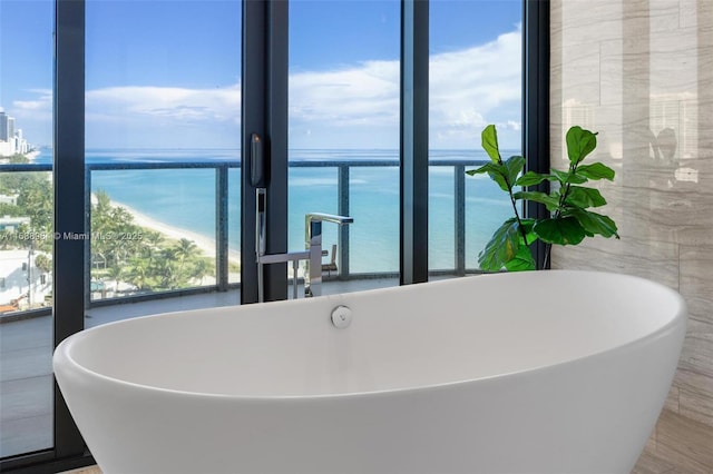 bathroom with plenty of natural light, a water view, and a bath