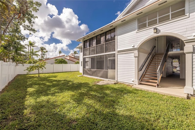 back of house with a fenced backyard, a lawn, and stairway