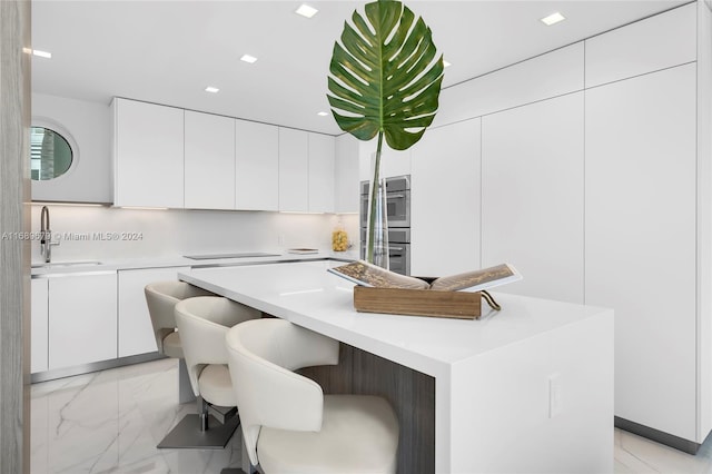 kitchen featuring white cabinetry, sink, a kitchen island, and double oven