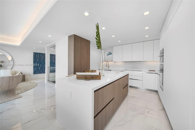 kitchen with white cabinetry, cooktop, and a kitchen island with sink