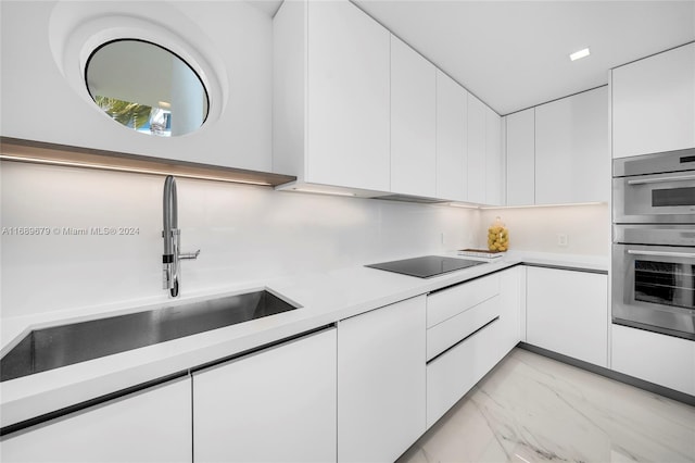 kitchen with sink, black electric stovetop, double oven, and white cabinets