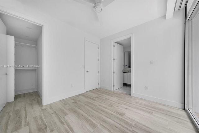 unfurnished bedroom featuring ensuite bathroom, ceiling fan, a closet, and light wood-type flooring