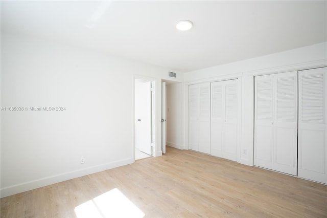 unfurnished bedroom with multiple closets and light hardwood / wood-style floors