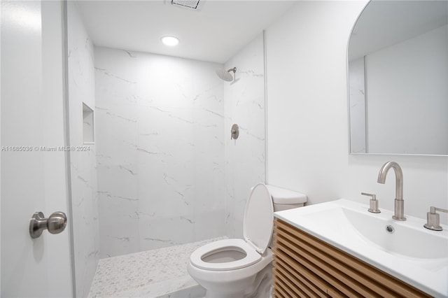 bathroom with toilet, vanity, and a tile shower