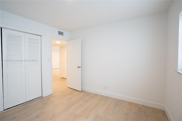 unfurnished bedroom with a closet and light wood-type flooring