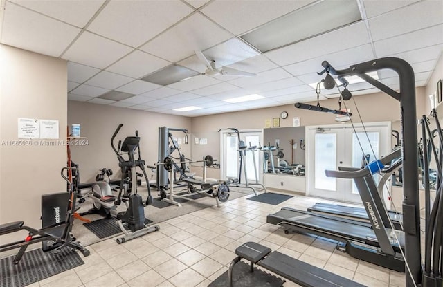 exercise room featuring a drop ceiling, light tile patterned floors, and ceiling fan