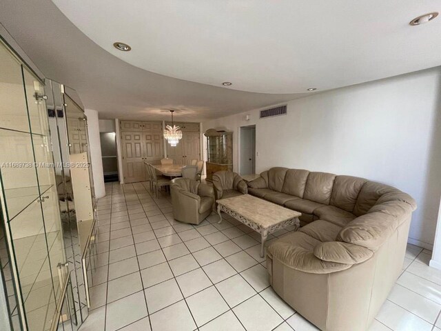 tiled living room with a notable chandelier