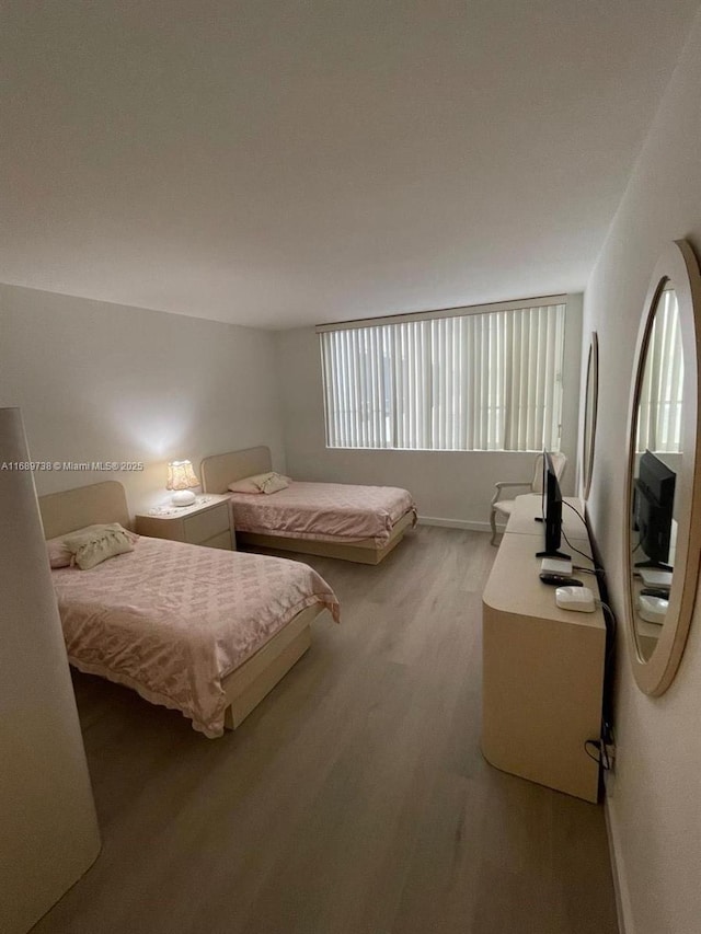 bedroom with light hardwood / wood-style floors and stainless steel refrigerator with ice dispenser