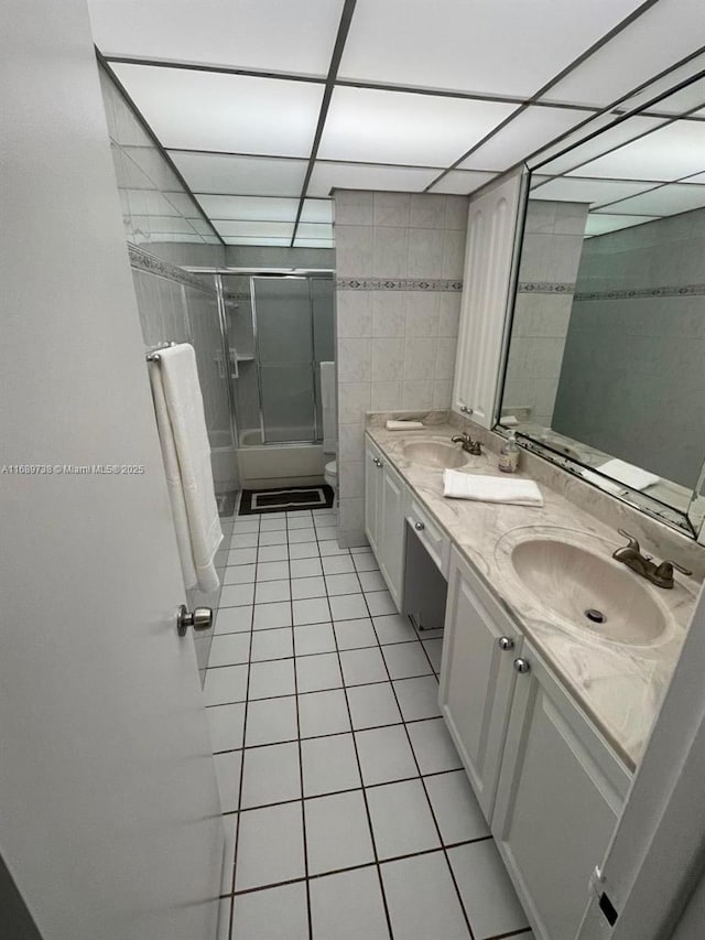 full bathroom with tile patterned flooring, combined bath / shower with glass door, toilet, vanity, and tile walls