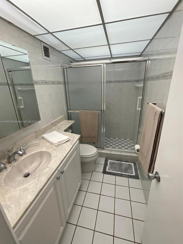 bathroom with vanity, tile patterned flooring, toilet, tile walls, and walk in shower