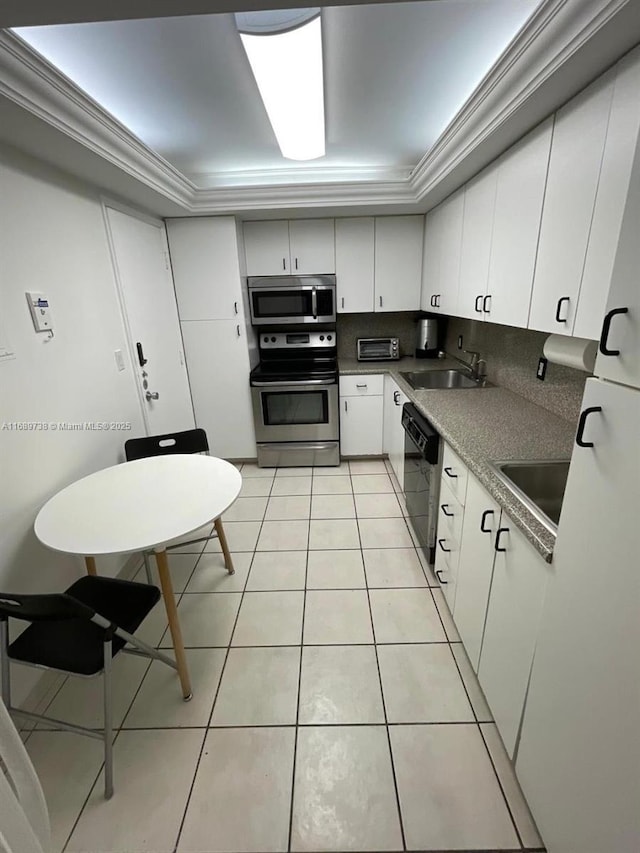 kitchen featuring a raised ceiling, sink, ornamental molding, white cabinetry, and stainless steel appliances