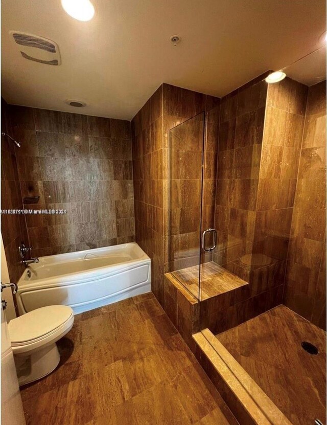 bathroom featuring shower with separate bathtub, toilet, and tile walls