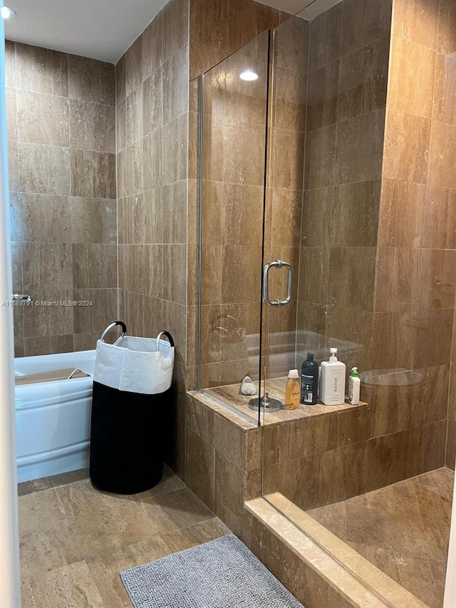 bathroom featuring tile walls and independent shower and bath