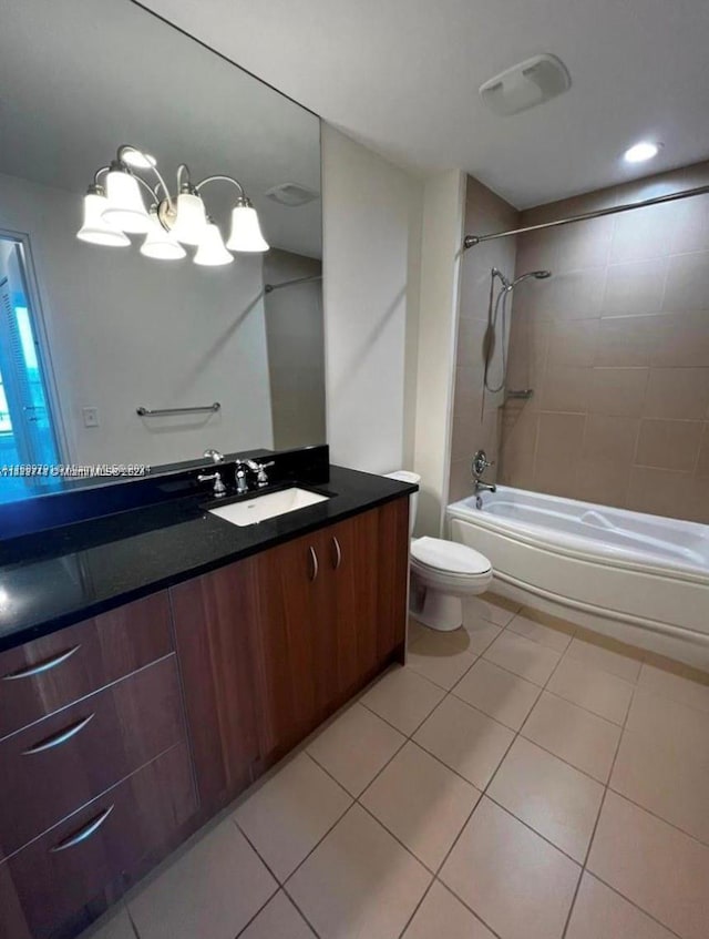 full bathroom featuring tiled shower / bath combo, a notable chandelier, tile patterned floors, toilet, and vanity