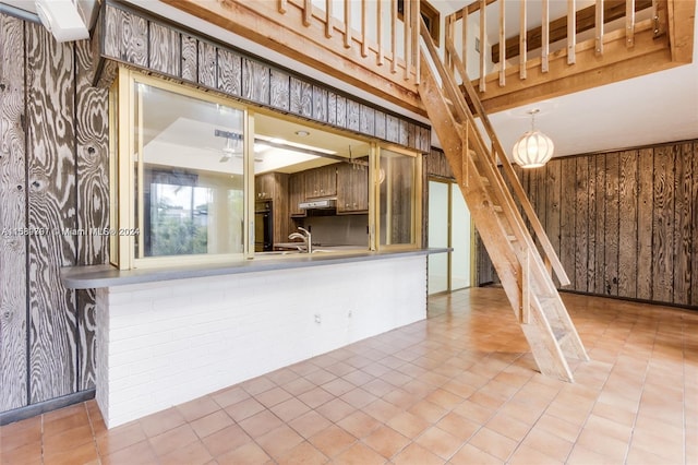 kitchen featuring black oven, wooden walls, sink, and tile patterned flooring