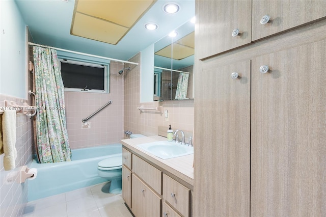 full bathroom featuring tile patterned flooring, shower / tub combo with curtain, vanity, toilet, and tile walls