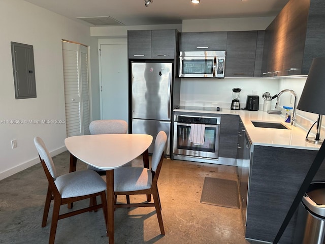 kitchen with sink, a breakfast bar area, gray cabinetry, appliances with stainless steel finishes, and electric panel