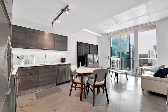 kitchen with sink, stainless steel appliances, dark brown cabinetry, track lighting, and expansive windows