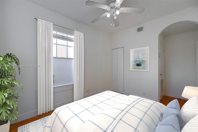 bedroom with hardwood / wood-style floors, ceiling fan, and a closet