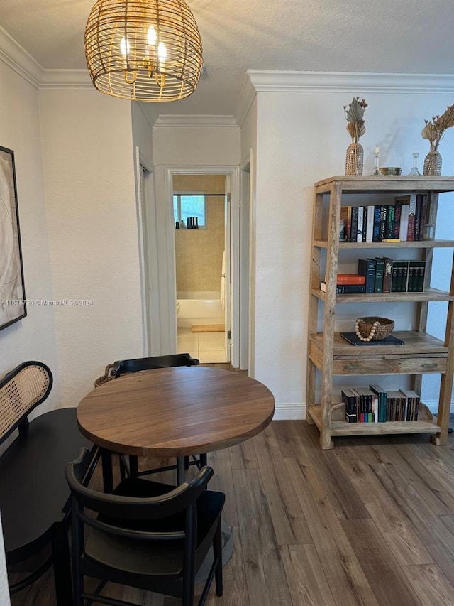 dining area with ornamental molding, wood-type flooring, and a textured ceiling