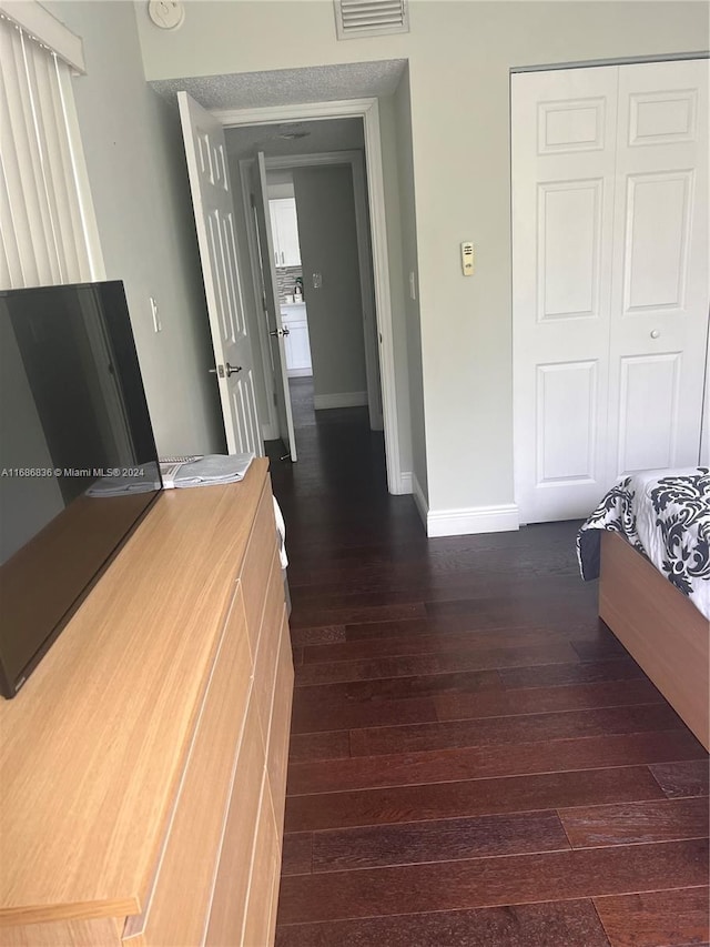 bedroom with dark hardwood / wood-style flooring, a closet, and a textured ceiling