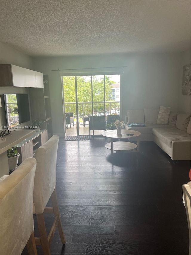 living room with dark wood-type flooring and a textured ceiling