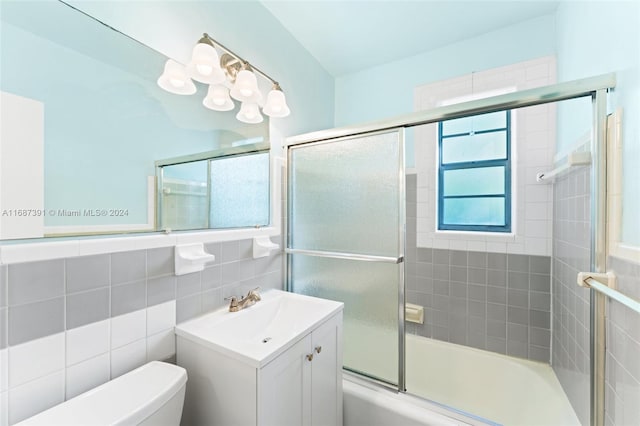 full bathroom featuring tile walls, enclosed tub / shower combo, toilet, and vanity