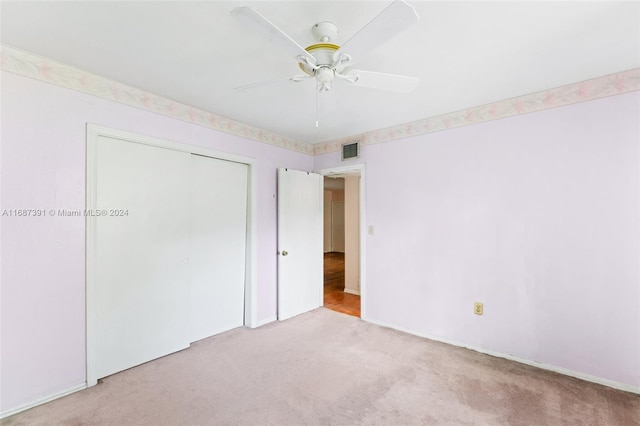 unfurnished bedroom featuring ceiling fan, light carpet, and a closet