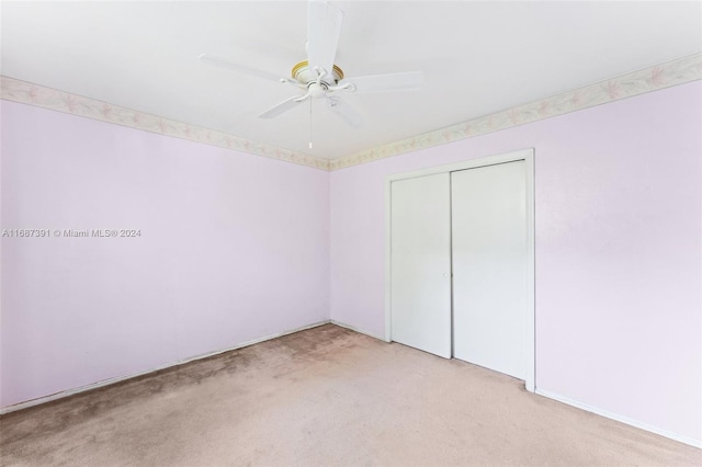 unfurnished bedroom featuring ceiling fan, a closet, and light colored carpet