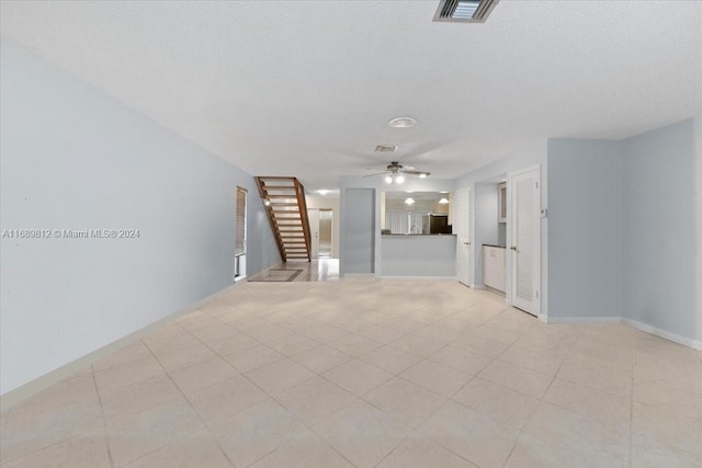 unfurnished living room with ceiling fan and a textured ceiling